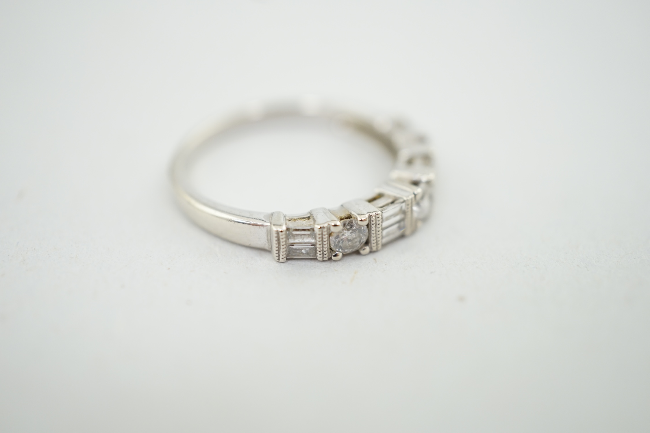 A modern 14k white gold, baguette and round cut diamond set half eternity ring